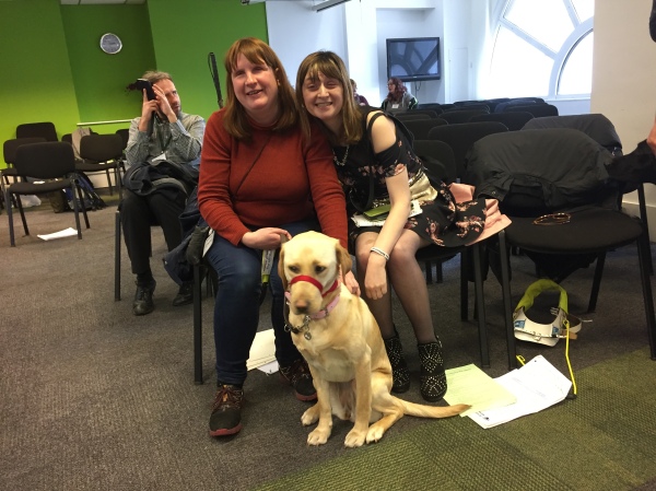 Fern and her guide dog sitting with one of our delegates